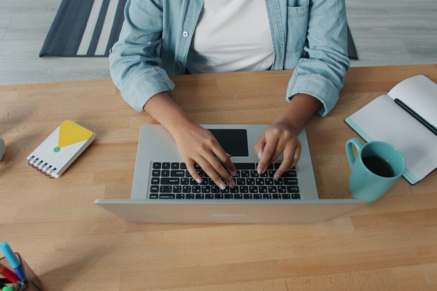 Person typing laptop home office desk