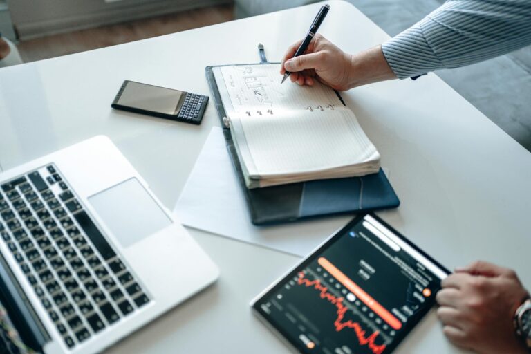 Person planning investments notebook laptop charts