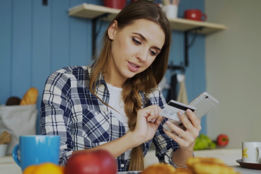 Woman checking bank account smartphone kitchen table