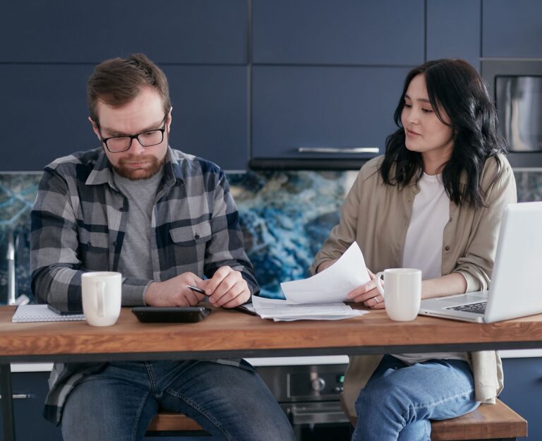Worried person kitchen table laptop bills notebook