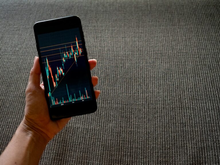 Hand holding falling stock chart phone