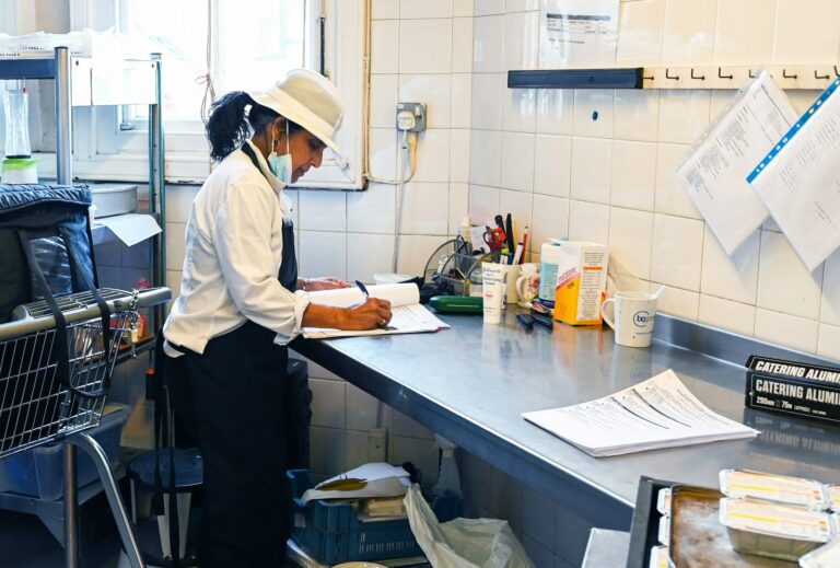Person writing shopping list kitchen counter