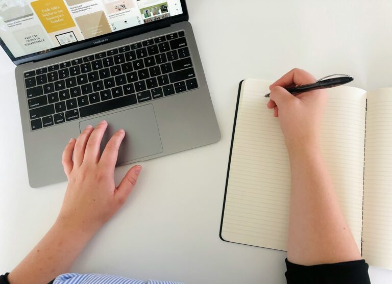 Person writing finance goals notebook desk